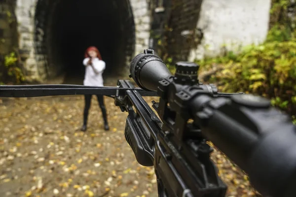 woman shooting with bow and arrow. crossbow and gun on belt. girl with gun opposite.