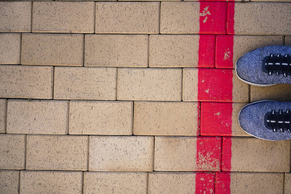 Синие спортивные туфли стоят на красной линии. Пересечение предела
