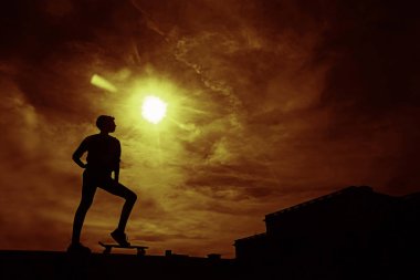 Kaykaycı iş başında. Güneş arka plan ile gökyüzünde paten parkta sörf paten hile yapan genç kadının siyah siluet. 