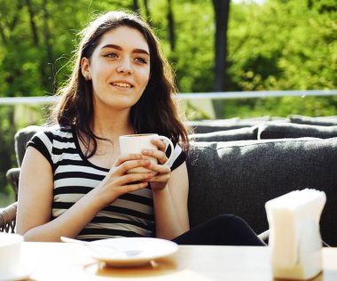 Kahve zamanı. Kaldırım kafede otururken kahve içen çekici genç kadın 