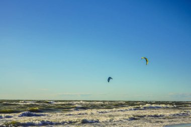 Mavi gökyüzü arka planında uçurtmaları olan sörfçü.