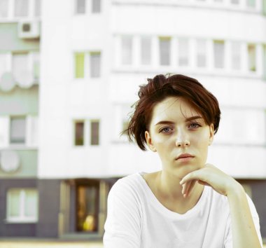 Beyaz gökdelen bina arka plan üzerinde koyu kısa saçlı güzel genç kız. 