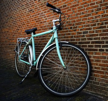 Kırmızı tuğla duvar yakınında duran sepet olmadan Mavi vintage şehir bisikleti.