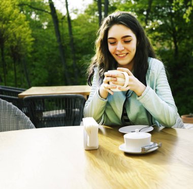 Kız kafenin balkonunda kahve fincan zevk. Sokak kafede kahve içen mutlu genç bayan Portresi. 