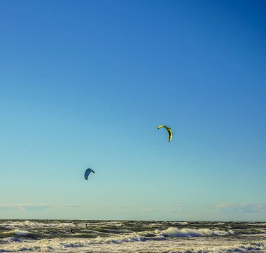 Mavi gökyüzü arka plan karşı uçurtma ile Surfers. Baltık denizinde sahilde iki sörfçü .2 deniz arka planda uçurtma sörfçü.
