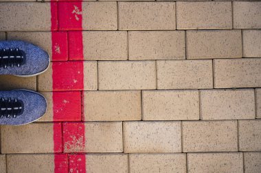 Kırmızı çizgide duran mavi sportif ayakkabılar. Sınırı aşma