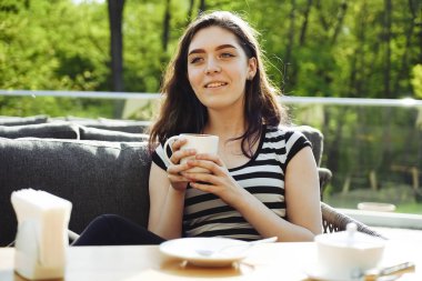 Kahve zamanı. Kaldırım kafede otururken kahve içen çekici genç kadın 