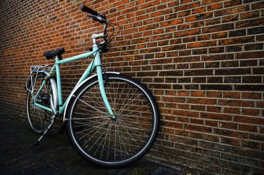 Kırmızı tuğla duvar yakınında duran sepet olmadan Mavi vintage şehir bisikleti.