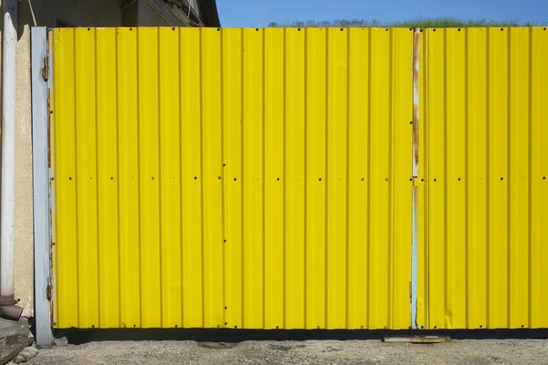 iron gate. Old zinc yellow color. Texture background of yellow corrugated fence.