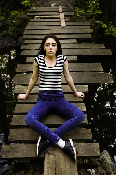 Młoda Kobieta Siedzi Zrelaksowany Drewnianym Moście Nad Rzeką — Zdjęcie stockowe