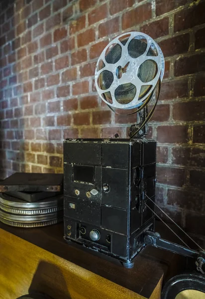 photo of an old movie projector on brick wall background. Old style movie projector, still-life, close-up.