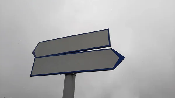 Two blank road signs pointing in opposite directions, blue sky background in vintage style.