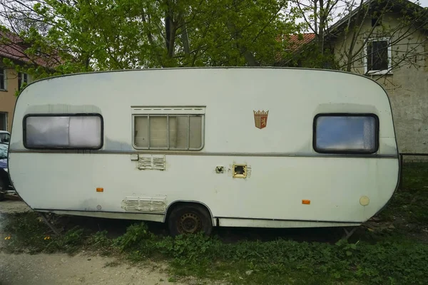 old rusty travel trailer (camper trailer, camper van, caravan). Side view.Caravan Trailer Near house. Summer Holidays Road Trip Travel Concept.emblem of berlin