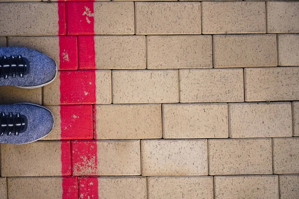 Kırmızı çizgide duran mavi sportif ayakkabılar. Sınırı aşma