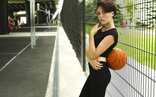 バスケットボールをしているスポーティな白人の女の子 スポーティな服を着て短いヘアカットの女の子 バスケットボールボールを持つ若い女性の肖像 — ストック写真