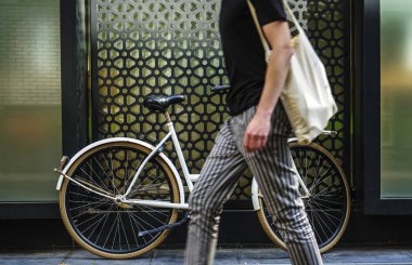 beyaz klasik ayakta beyaz bisiklet boyunca yürüyen yaya adam. yüz yok. çizgili pantolon ve siyah gömlek. 