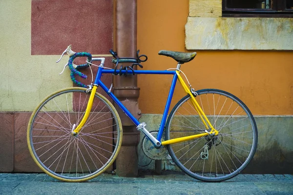 棕色和橙色墙壁背景上美丽的旧式蓝色自行车 蓝色和黄色的自行车停在外部 水泥墙背景 — 图库照片