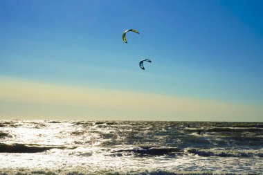 Mavi gökyüzü arka plan karşı uçurtma ile Surfers. Baltık denizinde sahilde iki sörfçü .2 deniz arka planda uçurtma sörfçü.