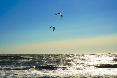 Mavi gökyüzü arka plan karşı uçurtma ile Surfers. Baltık denizinde sahilde iki sörfçü .2 deniz arka planda uçurtma sörfçü.