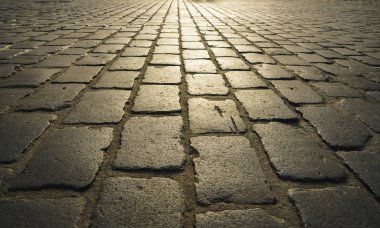 yürümek için arnavut kaldırım Stone arka plan. Granit bloklardan yapılmış bir duvar ile güneş ışığında Arnavut kaldırımlı sokak