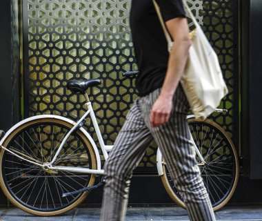 beyaz klasik ayakta beyaz bisiklet boyunca yürüyen yaya adam. yüz yok. çizgili pantolon ve siyah gömlek. 