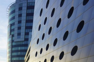 Cam ve beton modern yüksek katlı bina parçası. iş merkezinin cephesi. Gökyüzündeki bulutlar. Bina üzerindeki yuvarlak pencereler.