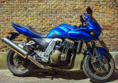 Haag, Hollanda - 31 Haziran 2019: Spor motokros motosiklet Kawasaki Z750s kırmızı tuğla duvar yakınındaki yaya bölgesinde park. 