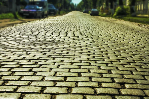 City street background with parked cars. Road paved with paving stones.Old cobblestone street with cars