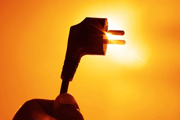 象征性的太阳能主题展示了太阳和天空 人类手拿着电源插座 太阳光穿过 插头和插座 太阳光 太阳能 — 图库照片