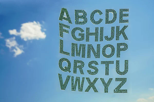 Set - the English alphabet from green rhinestones on blue sky background.