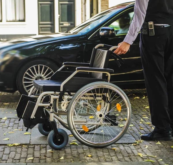 worker - employee gritting  a disabled person who came by taxi. hotel service. car parking near entrance. no face.