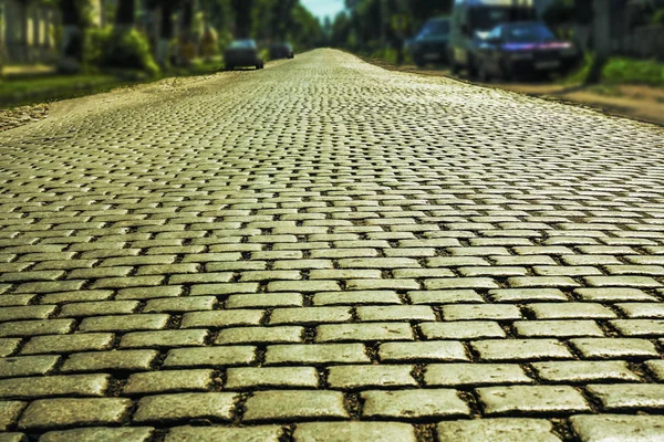 City street background with parked cars. Road paved with paving stones.Old cobblestone street with cars