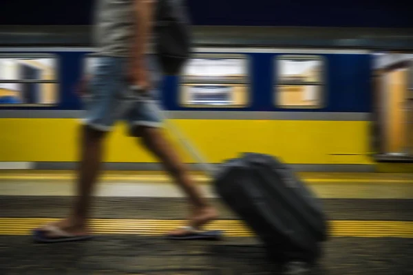 Blurred image. man with luggage waving at train station on wagon background. no face. railway station.