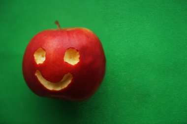 kavisli yüzü ile mutlu gülümseyen elma. Olumlu duygular. yeşil arka plan üzerinde mutlu kırmızı elma yüz. gülen yüz. 