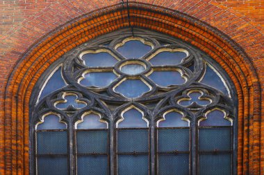 Big round church window with floral frame decoration.Round stone window on a church wall               