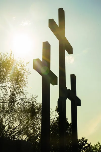 Three wooden crosses stand against a dramatic evening sky with radiant beams penetrating clouds. Great for Easter Sunday!