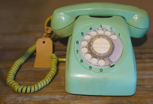 Old school light blue telephone on a wooden table background. Telecommunication. Vintage object