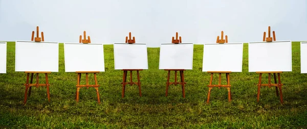 white Blank easel templates on green grass meadow background.