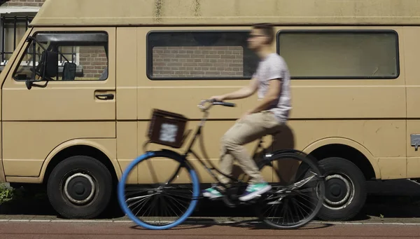 bicycle rider in Amsterdam, Holland in motion blur with a blurred minibus  in the background