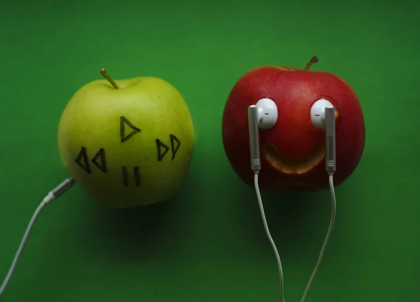 green apple in which headphones are connected. The music player in the shape of an apple with headphones.Fantasy on the theme of music and fruits. brand red apple.