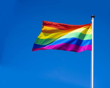 Gökkuşağı bayrağı (Lgbt hareketi) güneşli mavi gökyüzü arka planında 