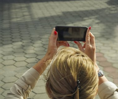 Arka manzara. Genç bir kadın tatil için şehir merkezine gidiyor. Fotoğraf çekmek için akıllı telefon kullanıyor.. 