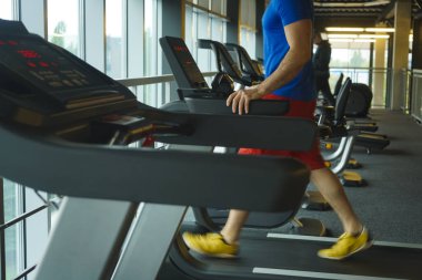 Spor salonunda koşu bandı takım çalışması yapan bir grup arkadaş. Genç adam koşu bandında antrenman yapıyor.. 