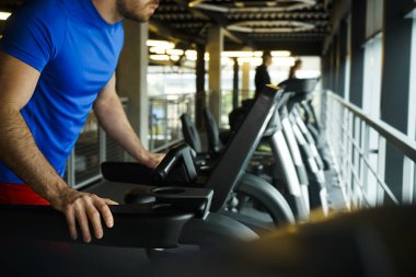 Spor salonunda koşu bandı takım çalışması yapan bir grup arkadaş. Genç adam koşu bandında antrenman yapıyor.. 