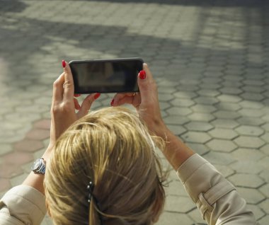Arka manzara. Genç bir kadın tatil için şehir merkezine gidiyor. Fotoğraf çekmek için akıllı telefon kullanıyor.. 