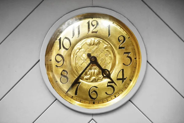 Vintage golden clock on gray wooden background.old classic yellow clock in a wooden wall.