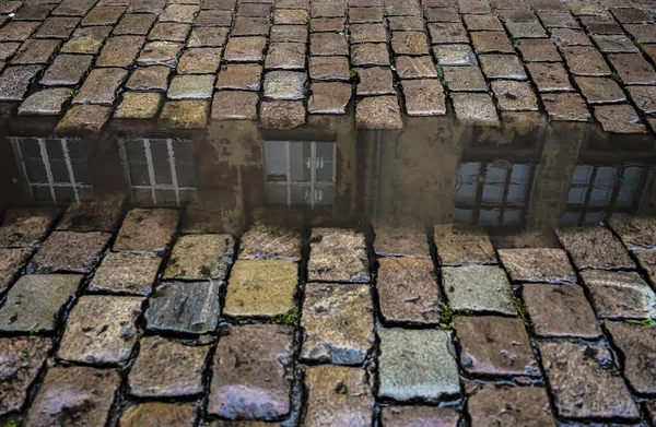 Cobblestones with reflection of house in puddle in the rain. circles on the water. paving stone - old european street . — Stock Image Cobblestones Reflection House Puddle Rain Circles Water Paving Stone Old Stock Image