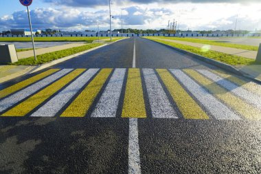 Beyaz ve sarı zebra yolda kesişiyor. siyah yeni modern asfalt. Bakış açısında boş ıslak yol. Yağmurdan sonra güneşli bir yaz günü