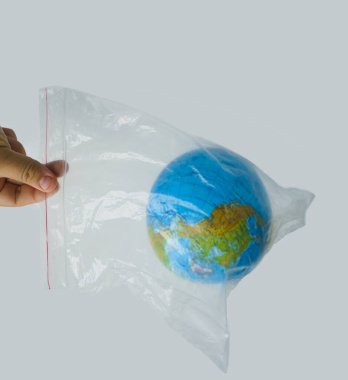 Erkek elini plastik torbaya koy. Dünya küresi beyaz arka planda izole edilmiş..
