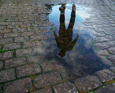 Su birikintisinin yanında duran adamın yansıması.